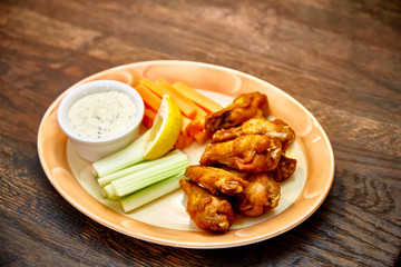 Fried chicken wings with vegetables and cheese sauce are on the plate