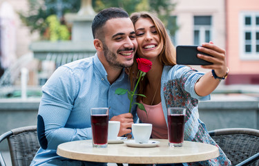 Couple sitting in the cafe and making a selfie with mobile phone. Relationships, love, romance, lifestyle, technology concept