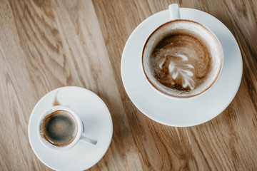cups of cappuccino and espresso on a wooden background