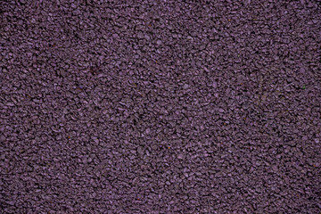 Fototapeta premium Mauve background from rubber coating of a sports ground. Recycled rubber tires are cut into small pieces, glued and painted in purple