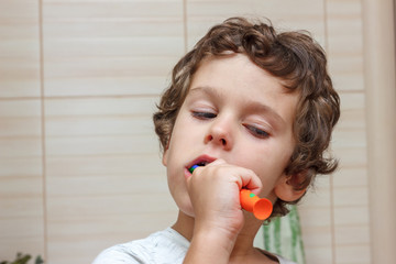 Little boy brushing his teeth in bathroom in front of mirror, oral hygiene