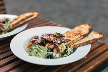 Fototapeta na wymiar Close up shot of caesar salad in cafe, organic green vegetable with parmesan cheese and bacon. Two plates