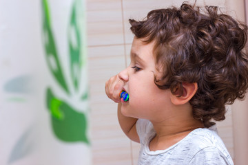 Little boy brushing his teeth in bathroom in front of mirror, oral hygiene
