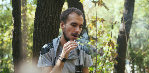 Man smoking . Bearded man smoking cigarette. Young man smoking a cigarette and producing smoke, outdoor hipster portrait. Mature hipster with beard.