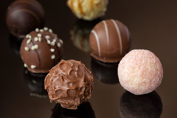 Round chocolates on a mirror surface . Sweets for the holiday. different chocolate