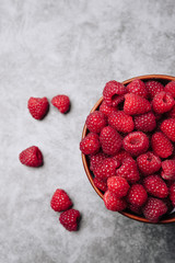 clay plate with tasty bright raspberries on a gray background