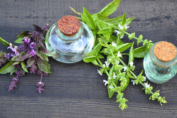 Oil with green and purple blooming basil close-up in a bottle on a wooden table in russian style