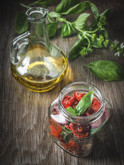 Dried tomatoes with basil leaves in olive oil.