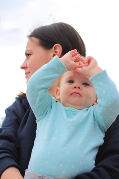 Small Child In Her Mother's Arms, Shot From Below