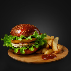 Appetizing burger with sauce and side dish on a wooden board.