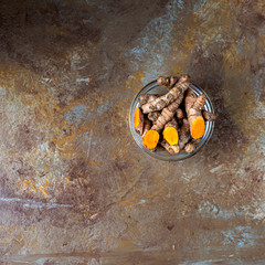 turmeric powder in jar dish on brown background