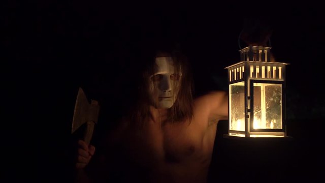 halloween, masked evil maniac  walking in the forest and looking for a victim