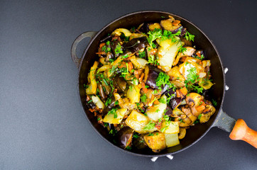 Fried eggplant, paprika and different vegetables in pan on black background