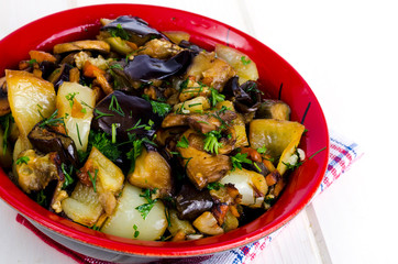 Vegetable saute with eggplants in ceramic bowl on white wooden table