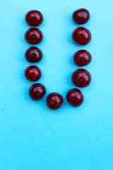Letter U fresh cherry alphabet blue color flat lay