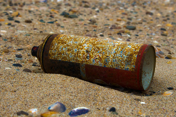  A rusty spray can on a beach. Pollute on the sand beach.