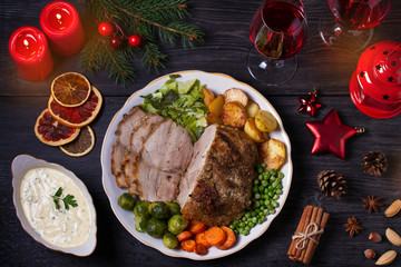Baked ham with vegetables two glasses of red wine. Christmas decorations. Dish for Christmas Eve. View from above, top studio shot