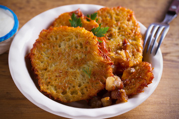 Potato pancakes with fried pork belly and onion in bowl