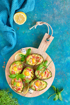 Top view on grilled avocado boats with bacon and egg, flat lay on turquoise background