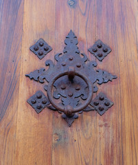 Fototapeta na wymiar Elegant ornamental old metal door knocker on weathered wooden door.