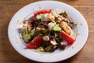 Healthy vegetarian food: tomato, cucumber, lettuce and mushroom salad with feta cheese and walnuts