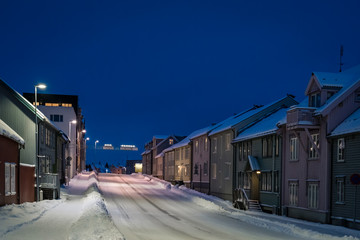 Empty snowy residential street in Tromso at dusk