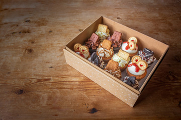 Box of fancy decorated cupcakes on wooden table