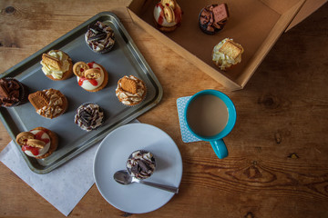 Iced cupcakes on baking sheet and served on plate with coffee