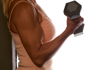 Side view of anonymous female weightlifter arm holding metal weight flexing bicep over white, not...