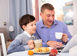 Obraz na płótnie Canvas Happy boy with father using laptop