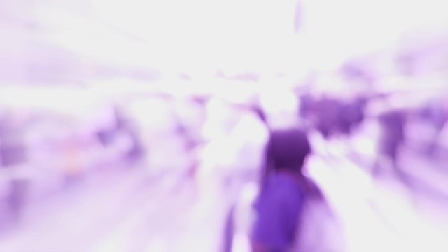 Abstract defocused view of busy city intersection with silhouettes of people walking in slow motion toward iridescent light purple colored human silhouettes