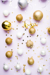 christmas balls arranged on a violet background, christmas concept and idea, golden , silver and white balls with confetti, flatly composition, christmas glitter holiday,  Xmas patter and background.