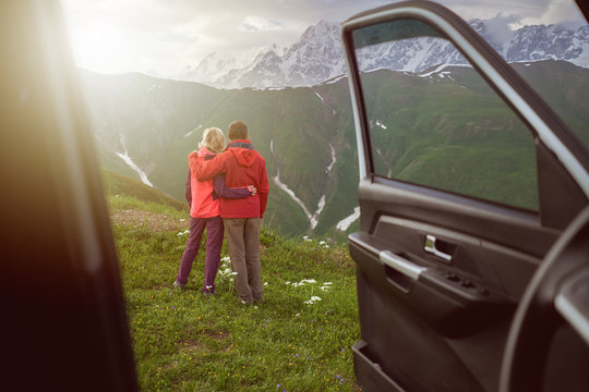 Happy couple hugs on beautiful nature and mountains out of car 