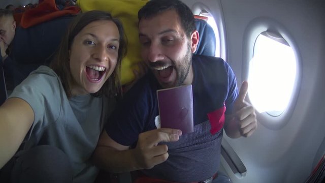handsome couple man and woman on travel take photo selfie inside airplane - Cheerful tourists taking self photo with mobile phone into airplane - Concept of happiness and holidays