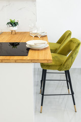 Modern minimalist open kitchen interior with wooden countertop vitroceramic cooking surface table setting with plates glasses high stools on white wall background. Nordic style