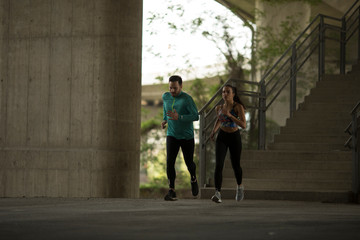 Handsome young couple running in urban environment at sunny day