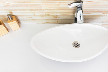Modern bathroom interior design white ceramic wash basin in oval shape tiled wall with wood texture set of soap and lotion dispensers. Minimalist ergonomic design in Scandinavian style