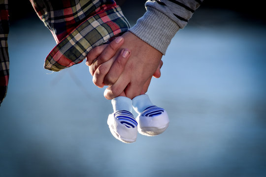 manos con escarpines de beb&eacute; en fondo de agua