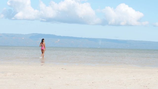 Sexy Filipina walks peacefully in a lovely tranquil beach in the Philippines.