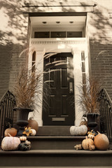 Toned retro style photo of typical of a front door and porch decorated with pumpkins for halloween...