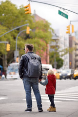 Little boy with his father looks on signal of traffic light on crossroads of New York City, USA. Traffic Laws.