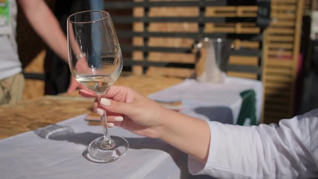 lady hand shakes white wine in tall glass at fest