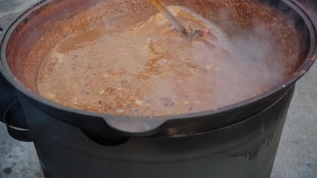 cook stirs traditional American chowder with ladle