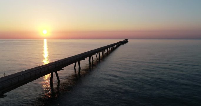 Sobrevolando con dron puente pantalan de puerto en un amanecer del mediterraneo