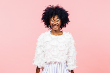 Portrait of a very happy young woman with black curly hair, isolated on pink studio background