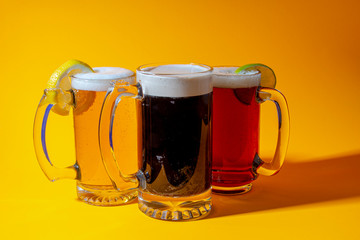 Ale, lager and Stout beer mugs on a orange background with a hard shadow on the right