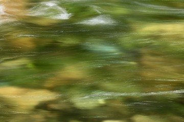 a slow shutter speed blurs the water and stones of a Sierra Nevada mountain stream  in California