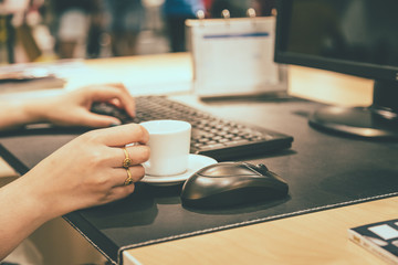 Woman hand holdding coffee cup with working table