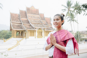 Portrait of Asian woman wearing Laos traditional clothing, acting greeting in front of the royal...