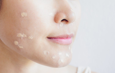 Close up shot of Asian woman side face marking and applying cream concealer on her facial skin. Concealer is a type of cosmetic that is used to mask dark circles, age spots, large pores etc.